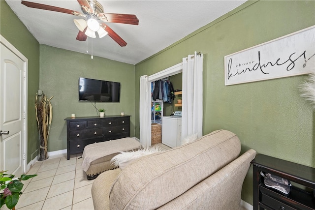 living room featuring ceiling fan, washer / dryer, and light tile patterned floors