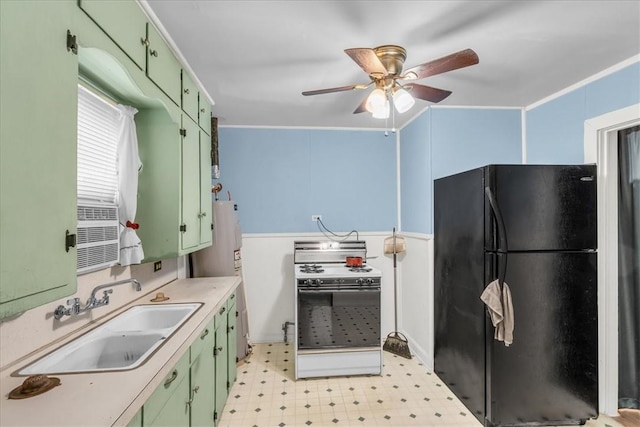 kitchen with stove, black fridge, sink, green cabinetry, and ceiling fan