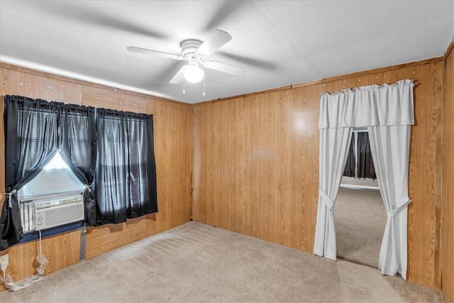 carpeted empty room featuring ceiling fan, cooling unit, and wooden walls