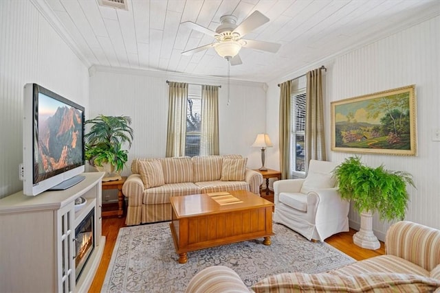 living area with ceiling fan, light wood-type flooring, wood ceiling, and ornamental molding