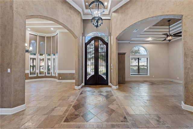 foyer entrance featuring french doors, ceiling fan with notable chandelier, and ornamental molding