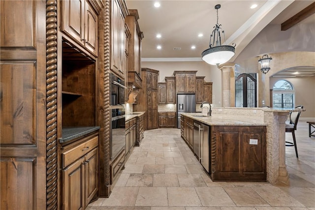 kitchen featuring a large island, sink, crown molding, decorative light fixtures, and a breakfast bar area