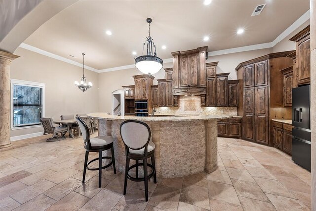 kitchen with tasteful backsplash, black fridge, dark brown cabinetry, a spacious island, and decorative light fixtures