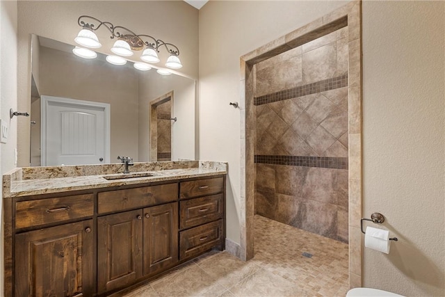 bathroom with tile patterned floors, vanity, and tiled shower