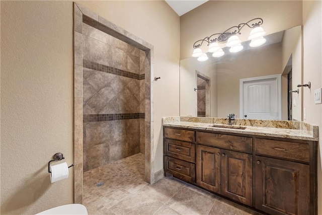 bathroom featuring a tile shower, tile patterned floors, and vanity