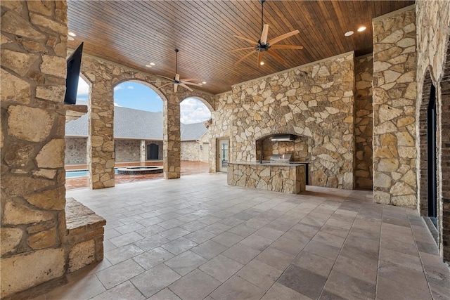 view of patio / terrace with ceiling fan, area for grilling, and an outdoor stone fireplace