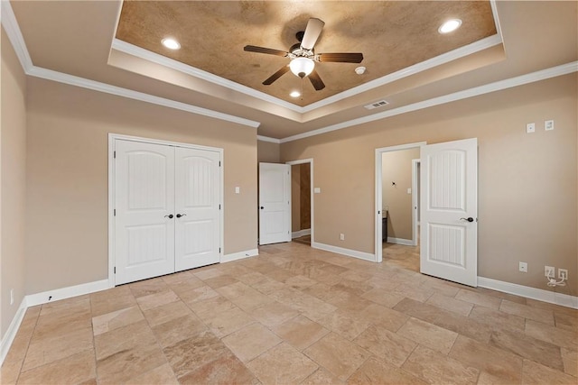 unfurnished bedroom with a tray ceiling, ceiling fan, and ornamental molding