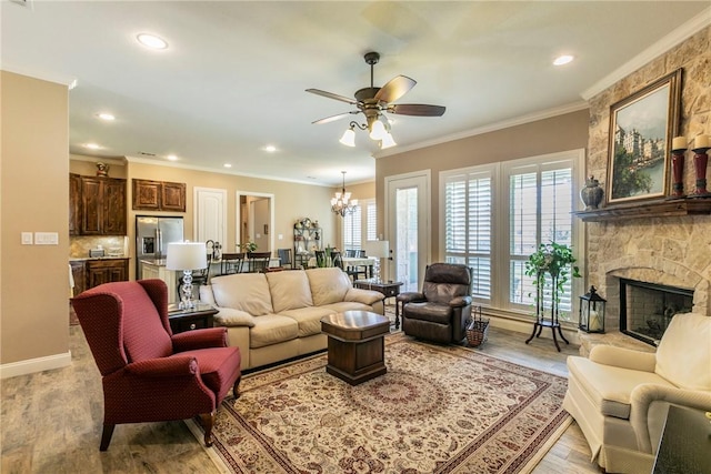 living room with ceiling fan with notable chandelier, a fireplace, light wood-type flooring, and ornamental molding