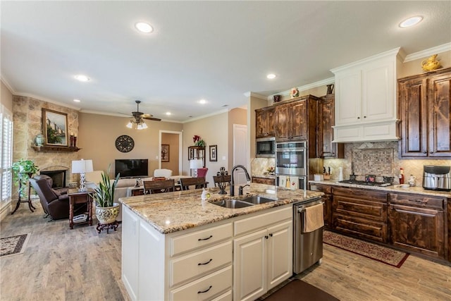 kitchen with appliances with stainless steel finishes, dark brown cabinetry, ceiling fan, a kitchen island with sink, and sink