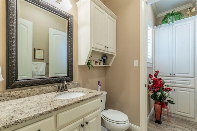 bathroom with wood-type flooring, vanity, toilet, and crown molding