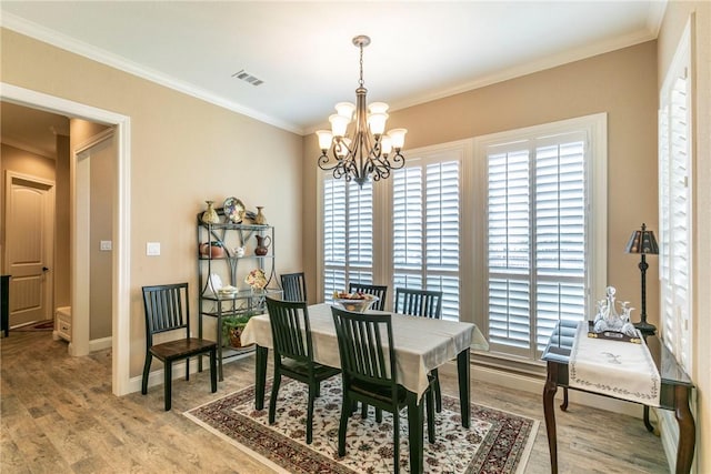 dining room featuring hardwood / wood-style floors, an inviting chandelier, and crown molding