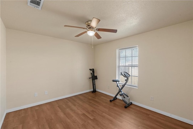 exercise room featuring hardwood / wood-style floors, a textured ceiling, and ceiling fan