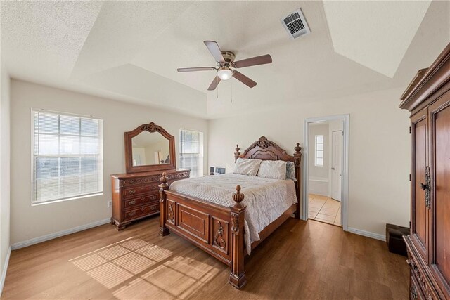 bedroom with dark hardwood / wood-style floors, a raised ceiling, and ceiling fan