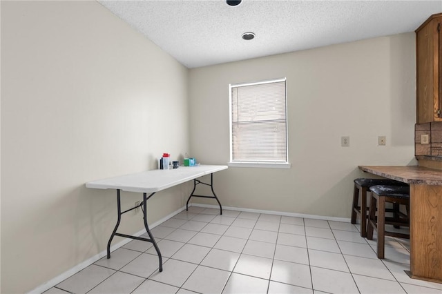 interior space featuring light tile patterned floors, baseboards, and a textured ceiling