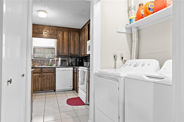 clothes washing area featuring washer and dryer, a sink, a textured ceiling, light tile patterned floors, and laundry area