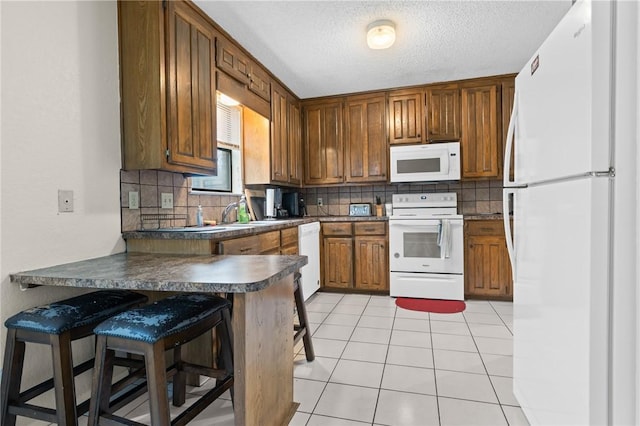 kitchen featuring white appliances, light tile patterned floors, a peninsula, decorative backsplash, and dark countertops