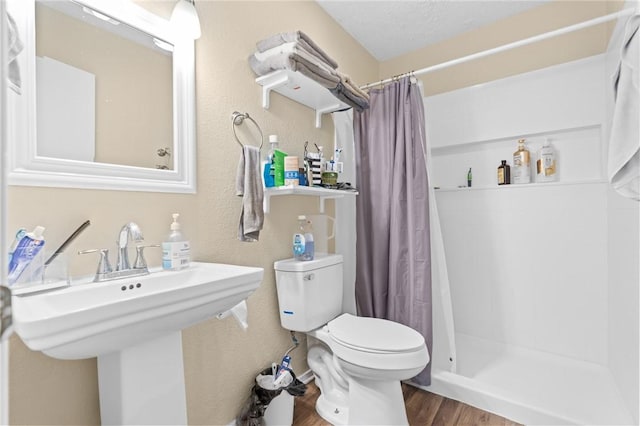 full bathroom featuring wood finished floors, toilet, and a stall shower