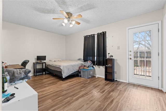 bedroom featuring light wood-style floors, access to exterior, and a textured ceiling