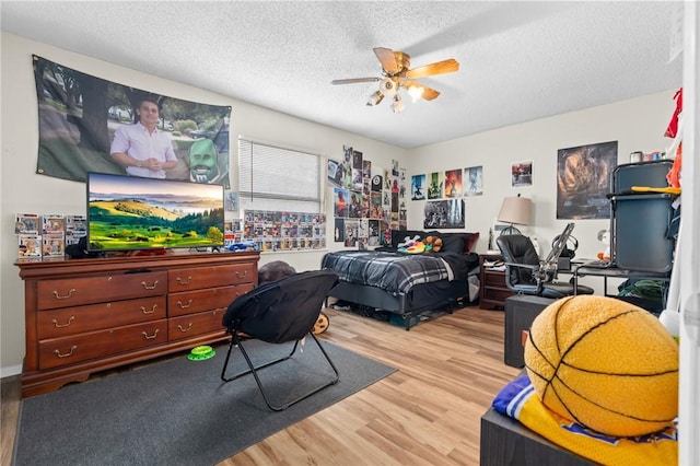 bedroom with a textured ceiling, a ceiling fan, and wood finished floors