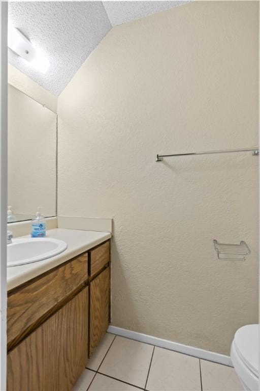 half bath featuring baseboards, vanity, a textured wall, tile patterned floors, and a textured ceiling