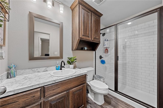 bathroom featuring hardwood / wood-style floors, vanity, a shower with shower door, and toilet