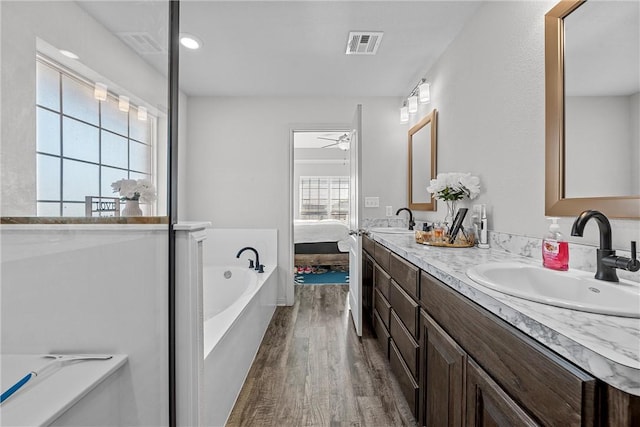 bathroom with wood-type flooring, vanity, plenty of natural light, and a tub