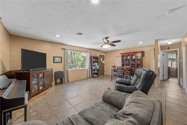 tiled living room with ceiling fan and a textured ceiling