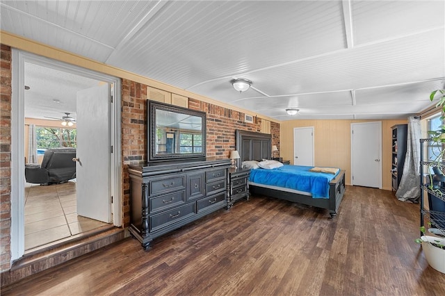 bedroom with brick wall and dark hardwood / wood-style floors