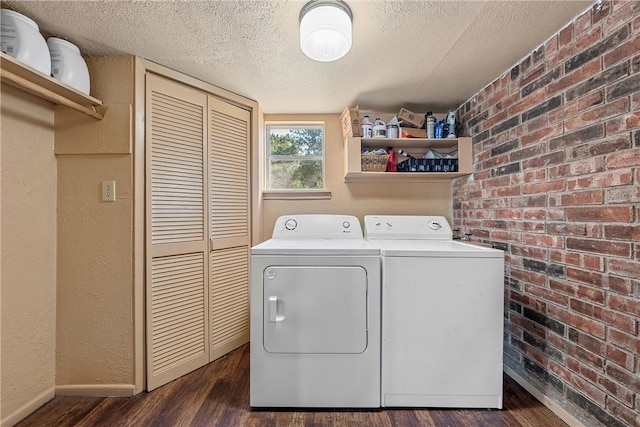 clothes washing area featuring separate washer and dryer, dark hardwood / wood-style flooring, brick wall, and a textured ceiling