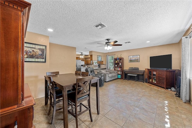 dining area featuring ceiling fan, light tile patterned flooring, and a textured ceiling