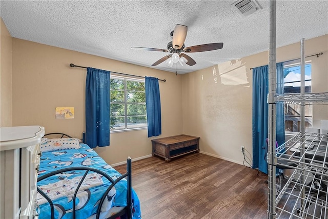 bedroom with ceiling fan, dark wood-type flooring, and a textured ceiling