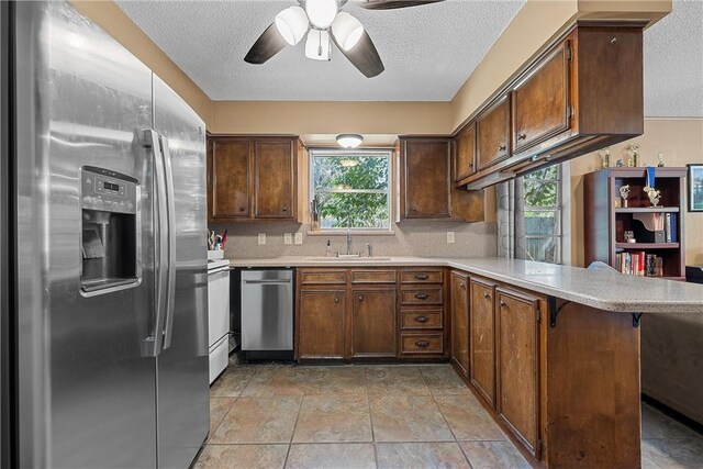 kitchen with kitchen peninsula, a kitchen breakfast bar, stainless steel appliances, and a wealth of natural light