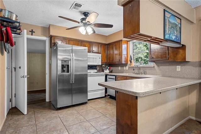 kitchen featuring ceiling fan, sink, stainless steel appliances, kitchen peninsula, and a textured ceiling