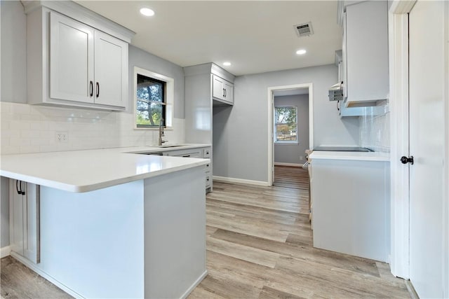 kitchen with a kitchen bar, kitchen peninsula, a healthy amount of sunlight, and light wood-type flooring