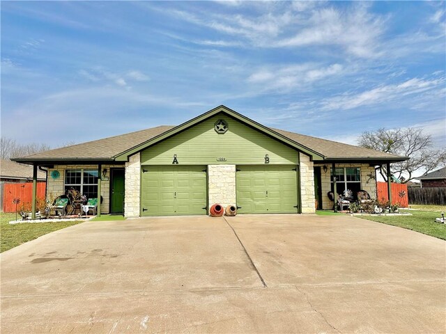 view of front of house with driveway, roof with shingles, a garage, and fence