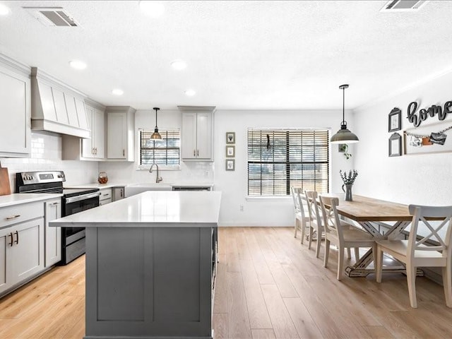 kitchen featuring pendant lighting, stainless steel electric range, gray cabinetry, a kitchen island, and custom exhaust hood