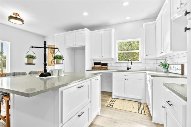 kitchen with light hardwood / wood-style floors, white cabinetry, a breakfast bar area, and a wealth of natural light