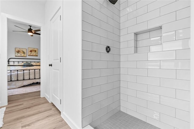 bathroom with a tile shower, hardwood / wood-style flooring, and ceiling fan