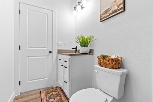 bathroom with hardwood / wood-style flooring, vanity, and toilet