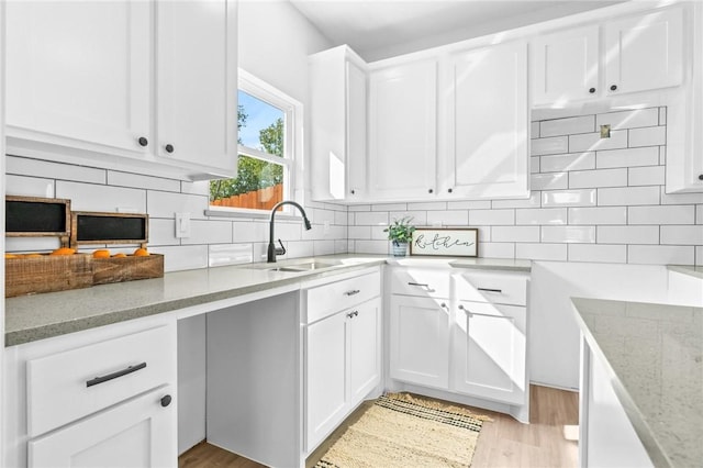 kitchen featuring decorative backsplash, light hardwood / wood-style floors, light stone counters, and white cabinetry