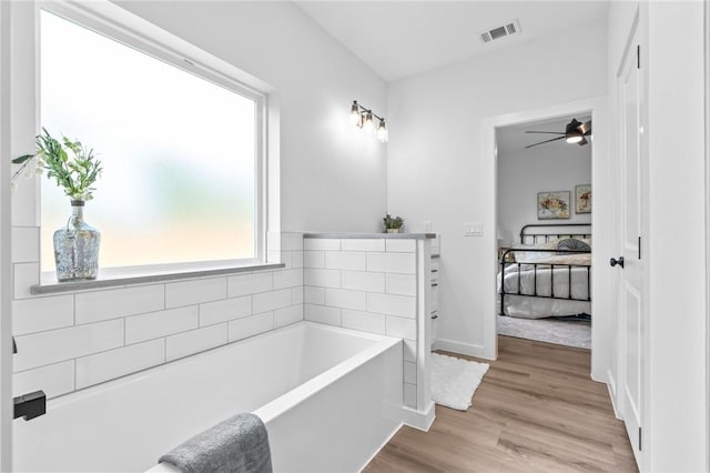 bathroom featuring vanity, ceiling fan, wood-type flooring, and a washtub