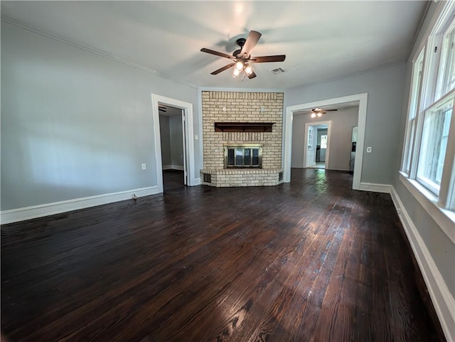 unfurnished living room featuring ceiling fan, crown molding, dark wood-type flooring, and a brick fireplace