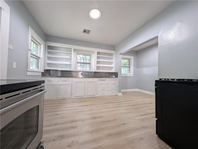 kitchen with white cabinetry, stainless steel stove, and light hardwood / wood-style floors