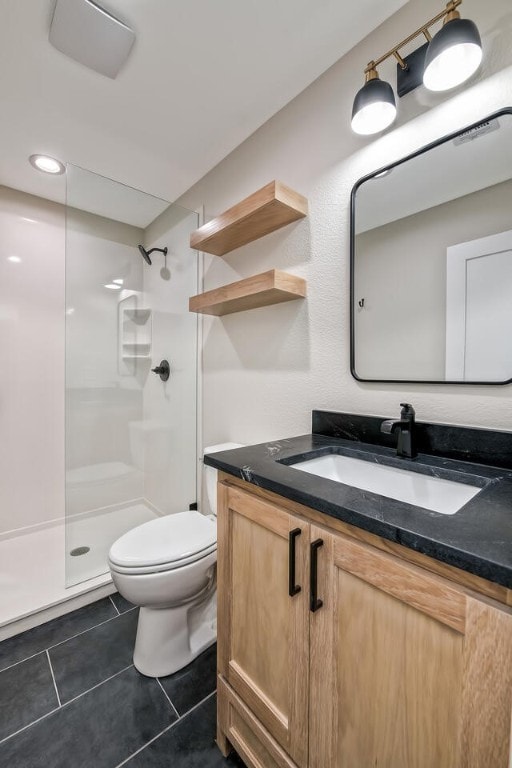 bathroom with tile patterned floors, vanity, toilet, and tiled shower