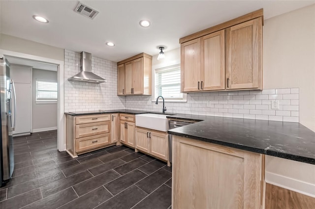 kitchen featuring sink, wall chimney exhaust hood, light brown cabinets, backsplash, and dark stone countertops