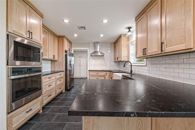 kitchen with sink, light brown cabinetry, wall chimney range hood, and appliances with stainless steel finishes