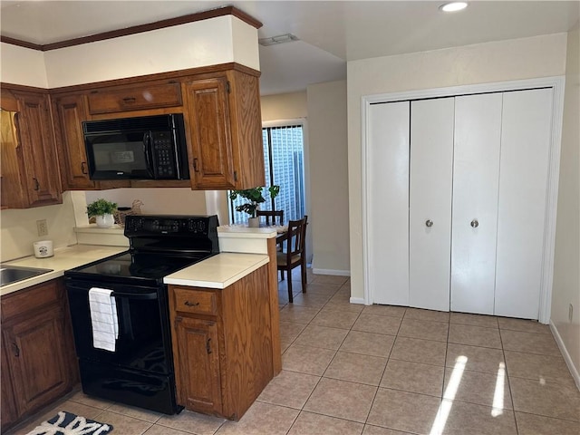 kitchen featuring black appliances, light tile patterned floors, and sink