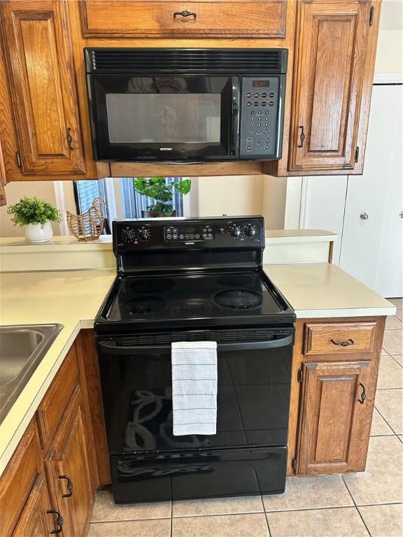 kitchen featuring sink, black appliances, kitchen peninsula, and light tile patterned flooring