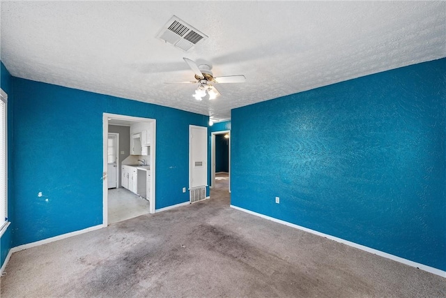 unfurnished room with ceiling fan, light colored carpet, and a textured ceiling