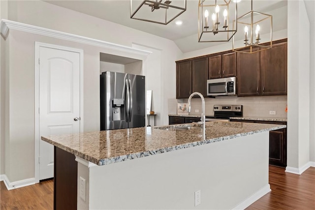 kitchen featuring hanging light fixtures, wood-type flooring, stainless steel appliances, and a kitchen island with sink